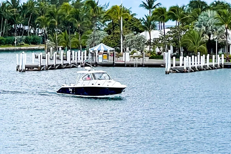 Slide: The Image of 2020 Pursuit OS 325 Offshore boat cruising near a tropical dock with palm trees. - 18