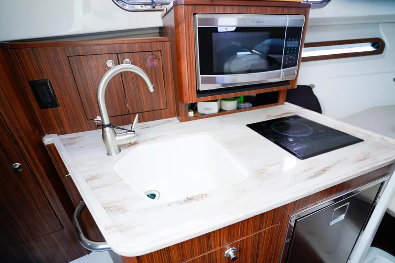 Slide: The Image of 2020 Pursuit OS 325 Offshore yacht kitchen with sink, microwave, and stovetop. - 30