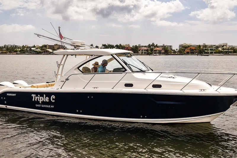 Slide: The Image of 2020 Pursuit OS 325 Offshore boat cruising on calm waters near a coastal city. - 40