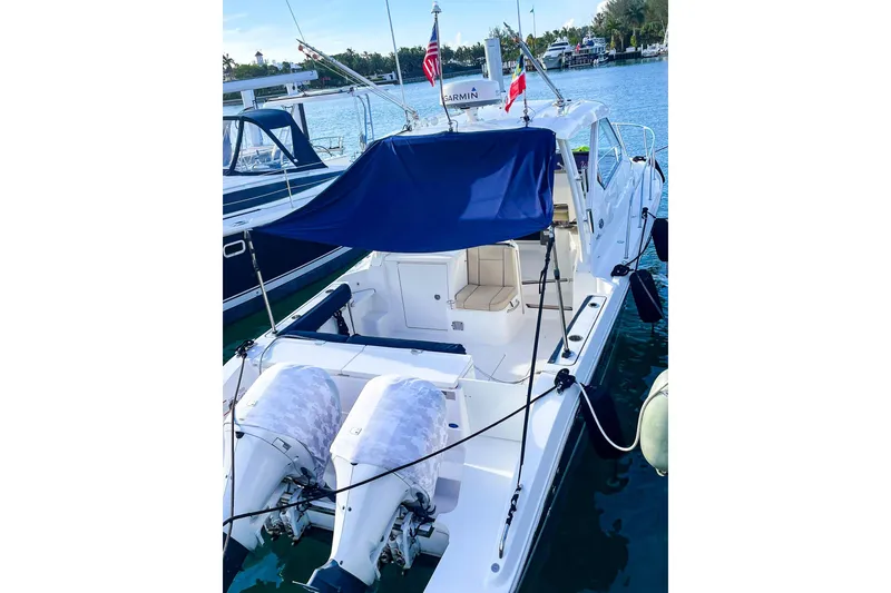 Slide: The Image of 2020 Pursuit OS 325 Offshore boat docked, featuring dual engines and a shaded seating area. - 7