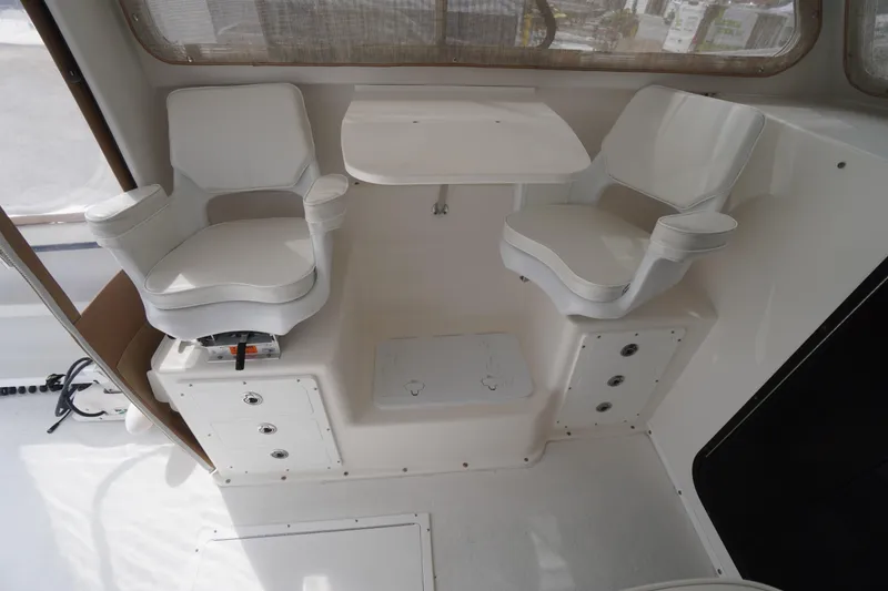 Slide: The Image of 2018 May-Craft 2700 Pilot XL interior with two white captain chairs and a small table. - 21