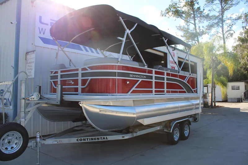 Slide: The Image of 2025 Bennington 20S pontoon boat on trailer, parked outdoors with canopy. - 3
