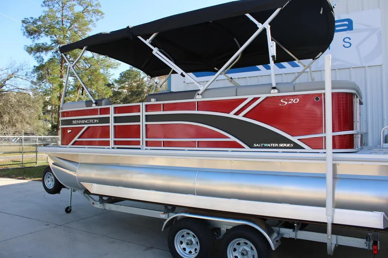Slide: The Image of 2025 Bennington 20S pontoon boat with red and silver design, parked on a trailer. - 9