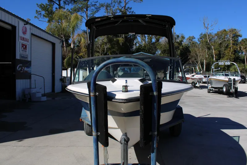 Slide: The Image of 1985 Correct Craft Ski Nautique boat on trailer at marina, surrounded by trees and other boats. - 3