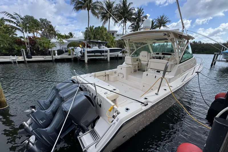 Slide: The Image of 2016 Grady-White Express 370 boat docked, featuring triple outboard engines and spacious deck. - 2
