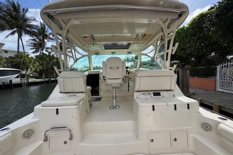 Slide: The Image of 2016 Grady-White Express 370 boat interior with seating and helm, docked by palm trees. - 8