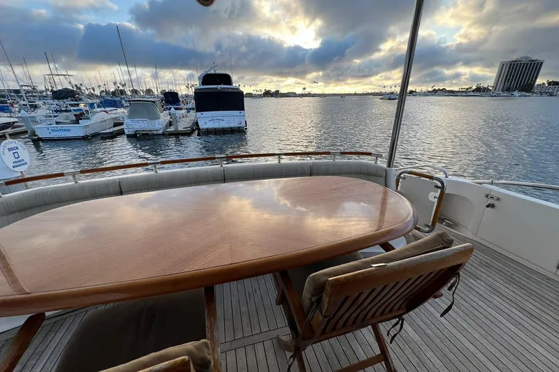 Slide: The Image of Luxury yacht deck view with wooden table, chairs, and marina backdrop at sunset. Lazzara 68, 2007. - 10