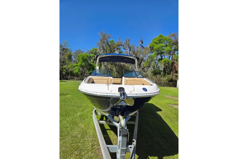 Slide: The Image of 2019 Sea Ray SDX 270 Outboard boat on trailer, set against a lush green landscape. - 2