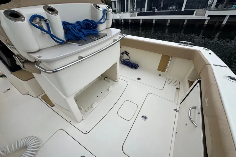 Slide: The Image of 2019 Scout 300 LXF boat interior with storage and seating, docked by the water. - 10