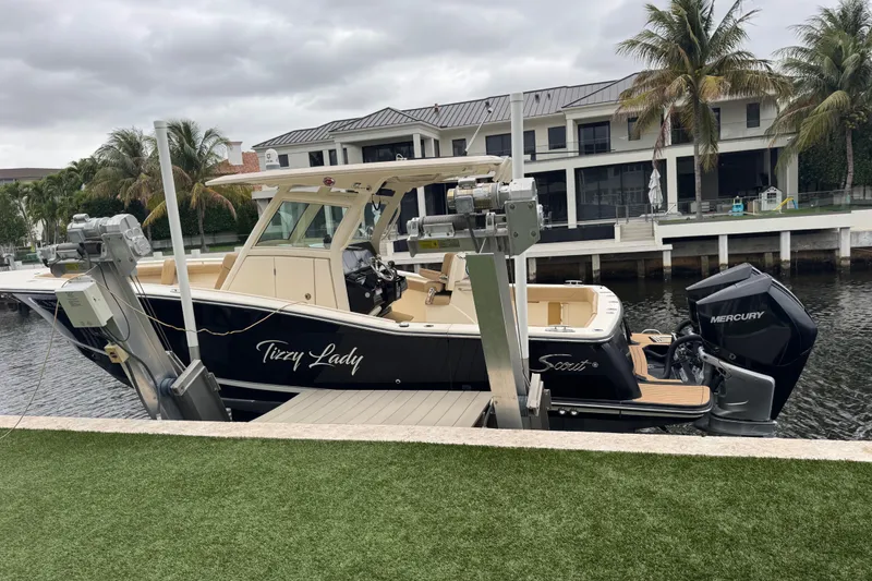 Slide: The Image of 2019 Scout 300 LXF boat docked by waterfront homes, featuring Mercury engines. - 12