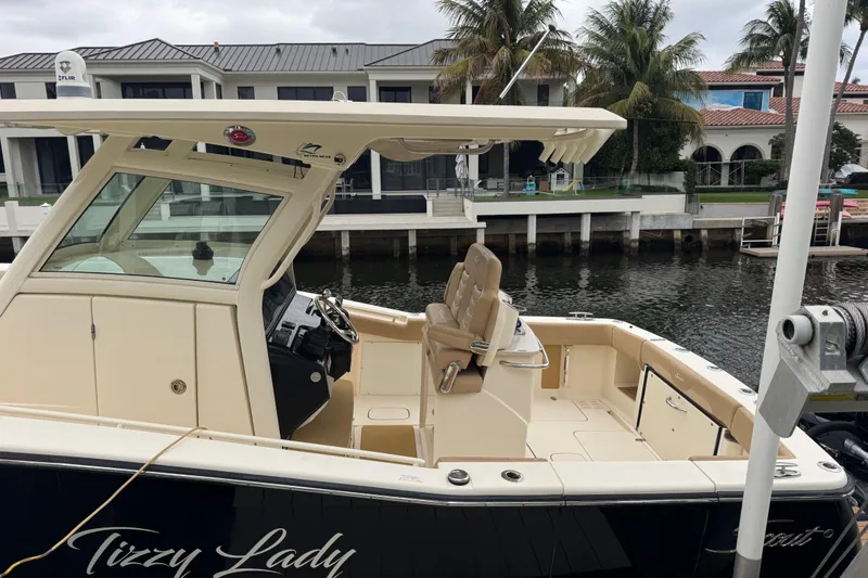 Slide: The Image of 2019 Scout 300 LXF boat docked by waterfront homes, featuring a spacious deck and helm. - 3