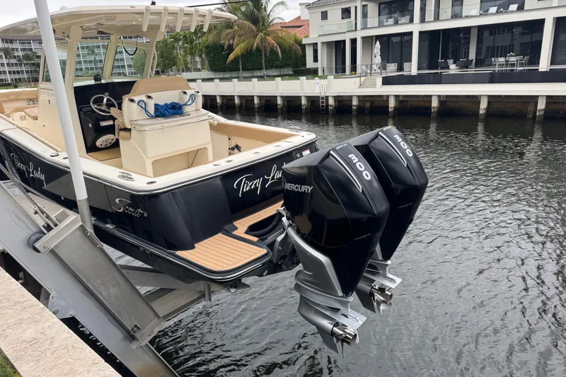 Slide: The Image of 2019 Scout 300 LXF boat with twin Mercury engines docked by waterfront homes. - 4