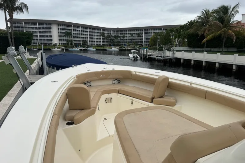 Slide: The Image of 2019 Scout 300 LXF boat docked near waterfront condos, featuring spacious seating. - 5