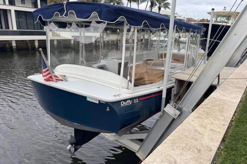 Slide: The Image of 2023 Duffy Bay Island 22 electric boat docked with canopy and American flag. - 3