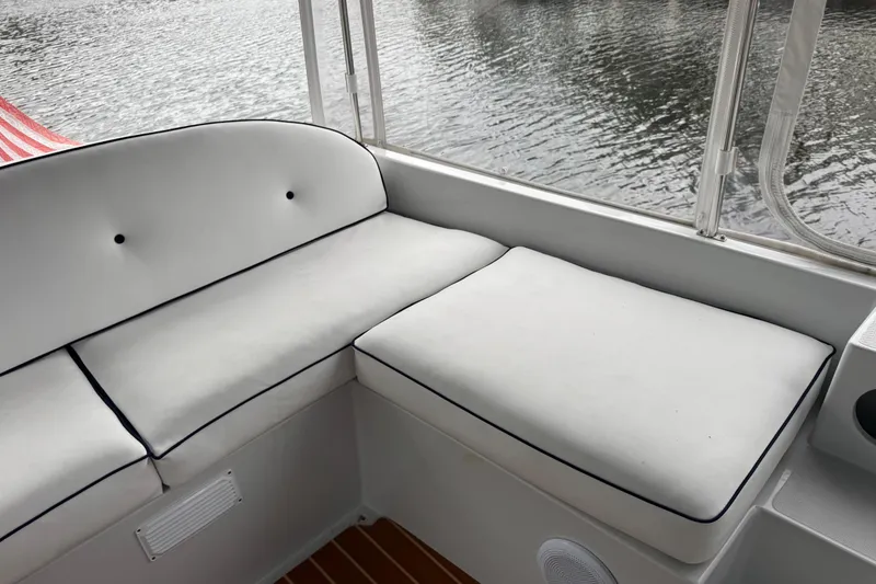 Slide: The Image of 2023 Duffy Bay Island 22 boat interior with white cushioned seating by the water. - 9