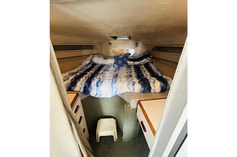 Slide: The Image of Cozy cabin interior of 1988 Sea Ray 265 Sedan Bridge with striped bedding and storage. - 10