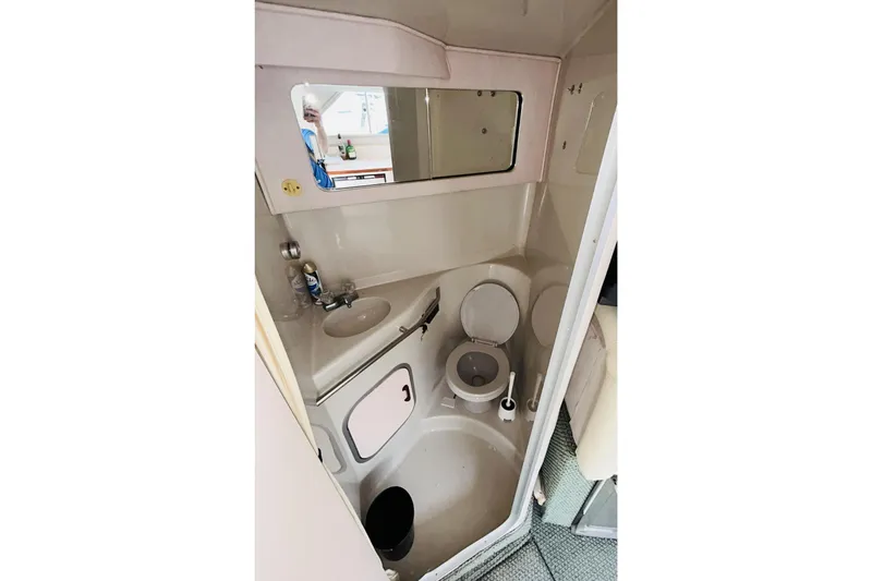 Slide: The Image of 1988 Sea Ray 265 Sedan Bridge bathroom with sink, toilet, and mirror. - 12