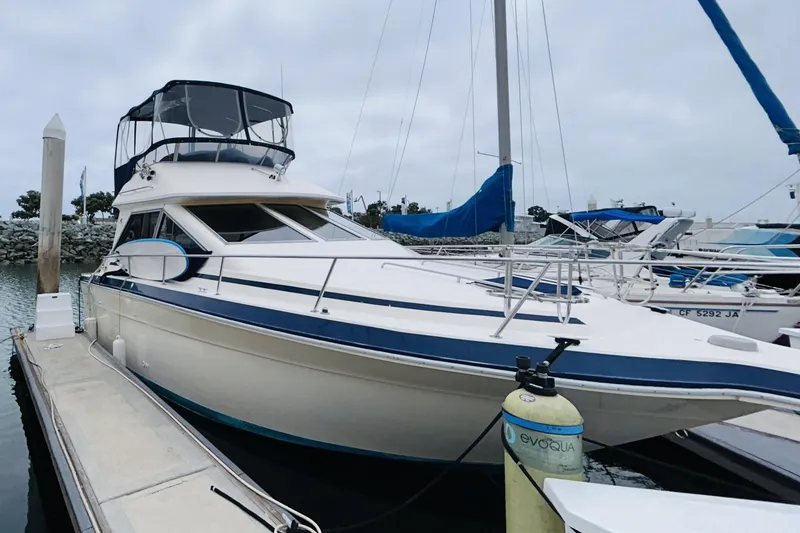 Slide: The Image of 1988 Sea Ray 265 Sedan Bridge docked at marina, featuring sleek design and blue accents. - 3
