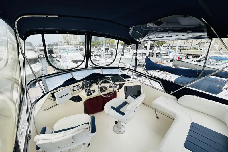 Slide: The Image of 1988 Sea Ray 265 Sedan Bridge helm with marina view, featuring navigation equipment and seating. - 6