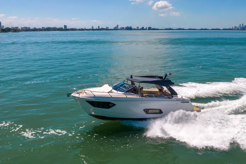 Slide: The Image of 2017 Absolute 40 STL yacht cruising on blue ocean with city skyline in background. - 92