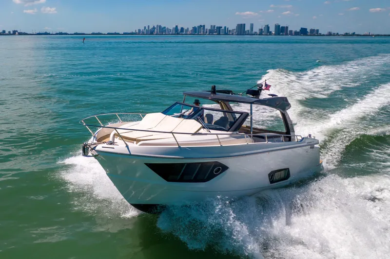 Slide: The Image of 2017 Absolute 40 STL yacht cruising on open water with city skyline backdrop. - 94