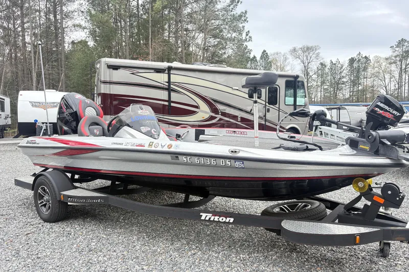 Slide: The Image of 2022 Triton 179 TrX boat on trailer, parked near RVs in a wooded area. - 4