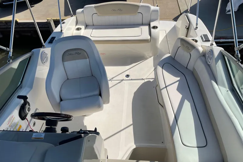 Slide: The Image of 2011 Sea Ray 240 Sundancer boat interior with white seating and steering wheel. - 10