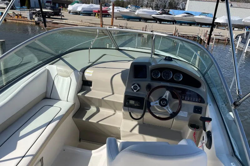 Slide: The Image of 2011 Sea Ray 240 Sundancer boat interior with steering wheel and dashboard at marina. - 11
