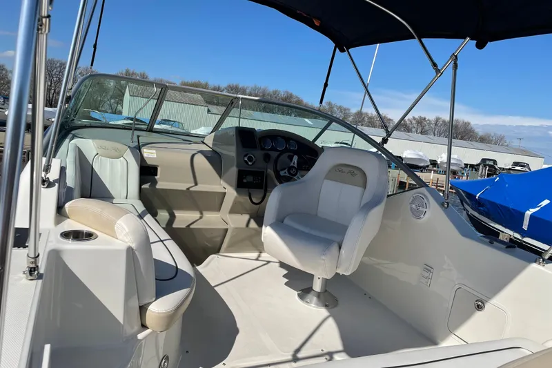 Slide: The Image of 2011 Sea Ray 240 Sundancer boat interior with helm and seating under blue sky. - 12