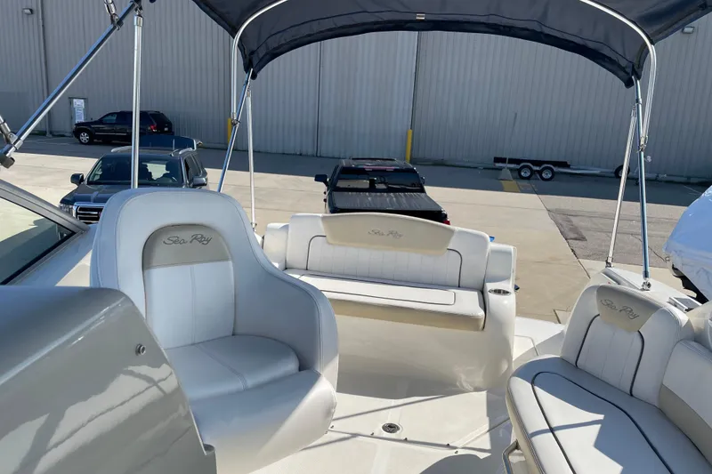 Slide: The Image of 2011 Sea Ray 240 Sundancer boat interior with seating and canopy in a parking area. - 14