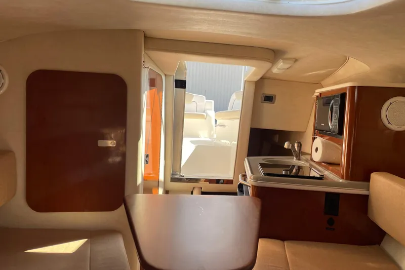 Slide: The Image of Interior of 2011 Sea Ray 240 Sundancer boat with kitchenette and seating area. - 18