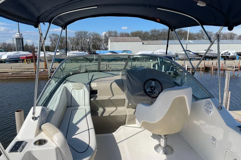 Slide: The Image of 2011 Sea Ray 240 Sundancer boat interior with helm, seating, and canopy at marina. - 9