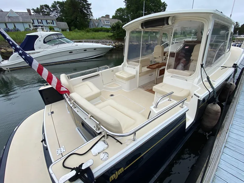 Slide: The Image of 2013 MJM 36z Downeast boat docked, featuring spacious seating and American flag. - 11