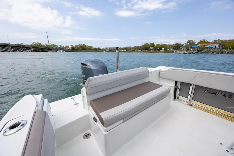 Slide: The Image of 2019 Blackfin 212 CC boat interior with seating, on a calm waterway under a blue sky. - 22