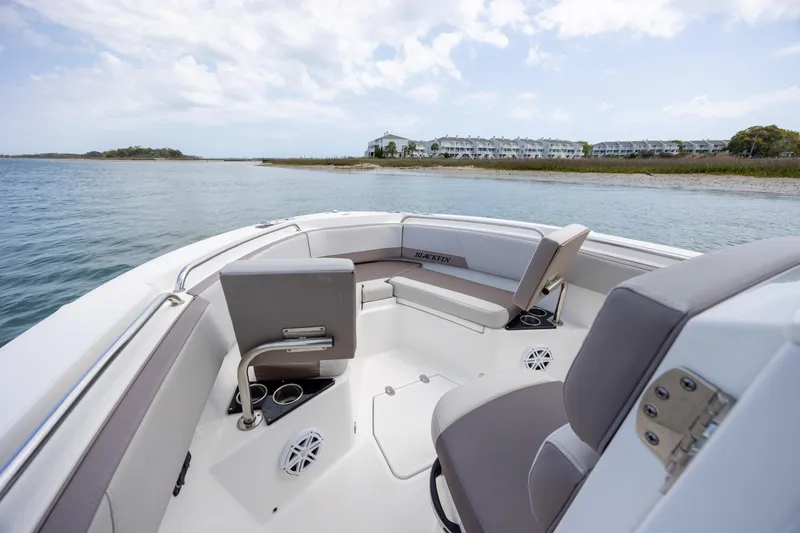 Slide: The Image of 2019 Blackfin 212 CC boat interior with seating, on calm water near shoreline. - 9