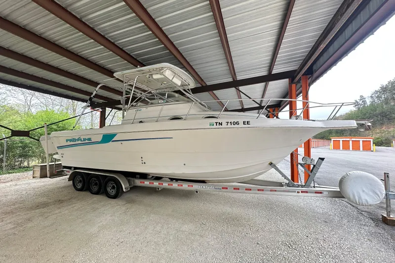 The Image of 1998 Pro-Line 2950 Walkaround boat on trailer under metal shelter. - 0