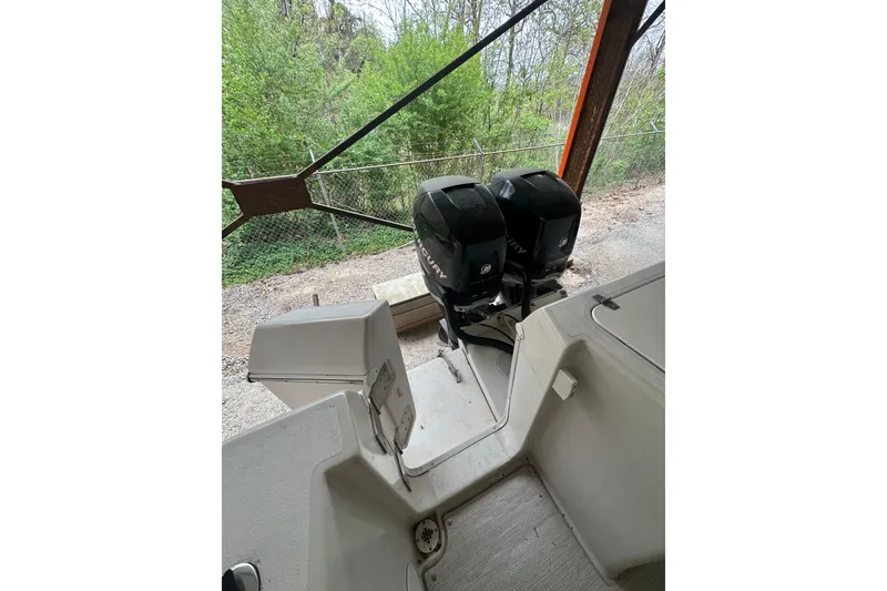 Slide: The Image of 1998 Pro-Line 2950 Walkaround boat with dual outboard motors, docked near greenery. - 3