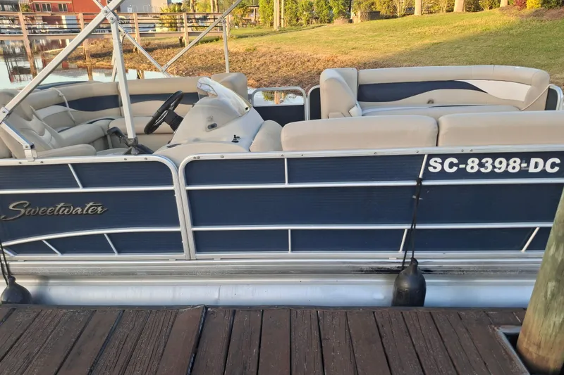 Slide: The Image of 2015 Godfrey Sweetwater 2286 C pontoon boat docked by a serene lakeside. - 1
