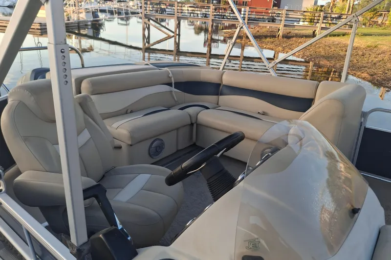 Slide: The Image of 2015 Godfrey Sweetwater 2286 C pontoon boat interior with plush seating and steering console. - 2