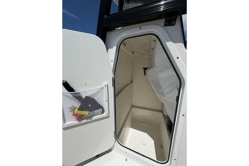 Slide: The Image of 2023 Sea Hunt Ultra 234 boat storage compartment with open door and mesh pocket. - 13