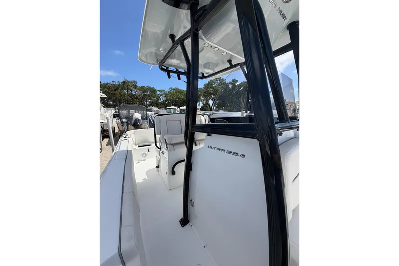 Slide: The Image of 2023 Sea Hunt Ultra 234 boat interior with seating and console, under clear blue sky. - 16