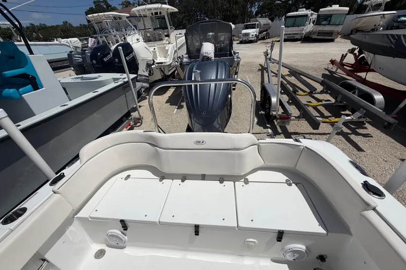 Slide: The Image of 2023 Sea Hunt Ultra 234 boat interior with seating and storage, parked among other boats. - 22