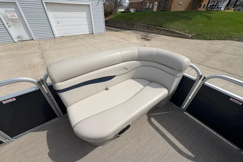 Slide: The Image of 2018 Bennington 188 SL pontoon boat with beige seating, parked on concrete. - 10
