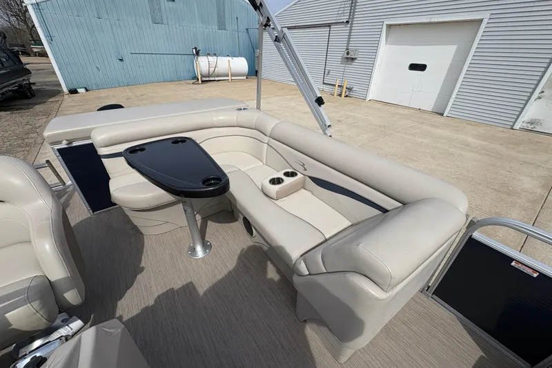 Slide: The Image of 2018 Bennington 188 SL pontoon boat with beige seating and black table, docked outdoors. - 13