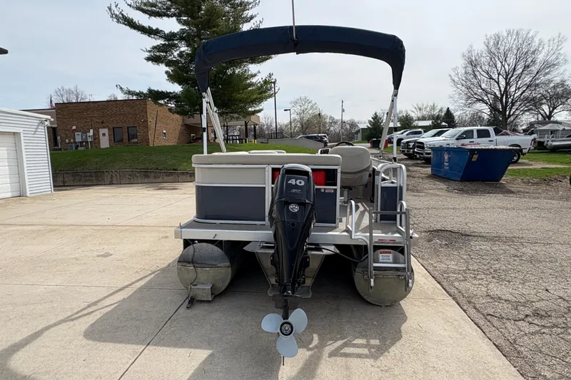 Slide: The Image of 2018 Bennington 188 SL pontoon boat with 40 HP engine, parked outdoors. - 2