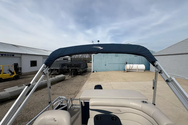 Slide: The Image of 2018 Bennington 188 SL pontoon boat with blue canopy in a marina setting. - 21