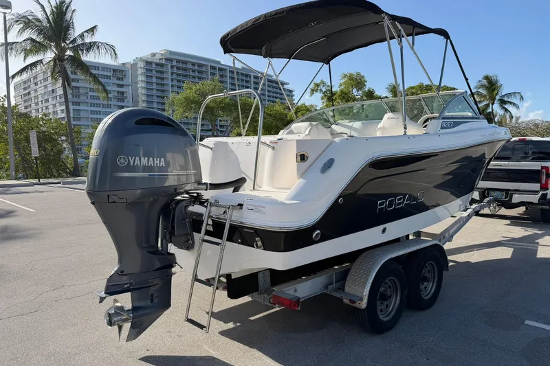 Slide: The Image of 2016 Robalo R227 Dual Console boat with Yamaha engine on trailer, parked near palm trees. - 5
