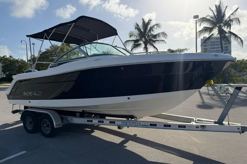 Slide: The Image of 2016 Robalo R227 Dual Console boat on trailer, parked under palm trees. - 7