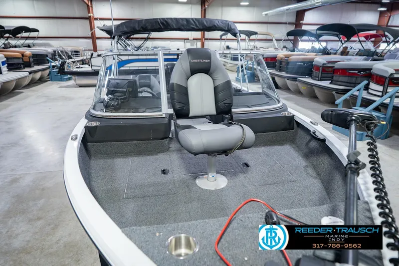 Slide: The Image of 2014 Crestliner 1650 Fish Hawk SE boat in showroom, featuring a central seat and modern design. - 13
