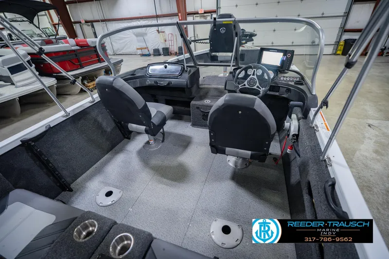 Slide: The Image of 2014 Crestliner 1650 Fish Hawk SE interior with dual seats and control panel in a showroom. - 14